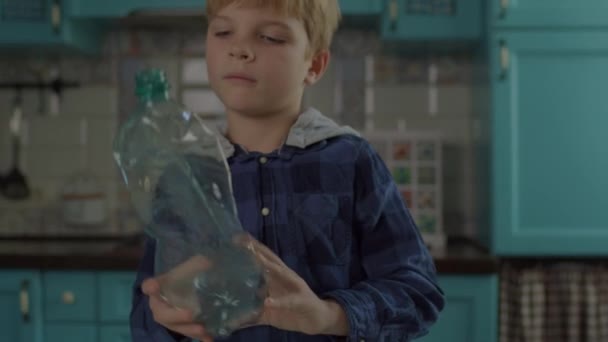 Дошкільний хлопчик сортує пластикові пляшки в ємності з зеленим значком переробки. Процес переробки будинку. Легко переробляти . — стокове відео