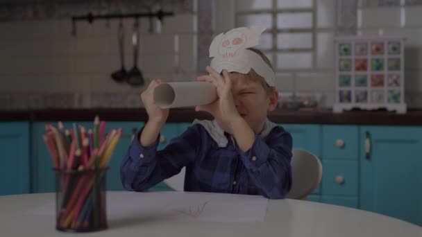 Παιδί παίζει πειρατές παιχνίδι με χάρτινο τηλεσκόπιο και καλύμματα κεφαλής με κρανίο και σταυρωτά κόκαλα. Νηπιαγωγείο σχέδιο με μολύβια χρώμα κάθεται μόνος στο σπίτι. — Αρχείο Βίντεο