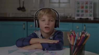 Kulaklıklı okul çocuğu kameraya bakarak konuşuyor. Webcam çocuk konuşması görüntüsü. Çevrimiçi eğitim ve çocuklar için uzaktan öğrenme. 