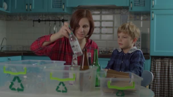 30 'ların anne ve oğlu evde geri dönüşüm atıklarını sıralıyor. Aile kağıtları, cam ve plastik geri dönüşümlü malzemeler yeşil geri dönüşüm işaretli kaplara ayrılır. — Stok video