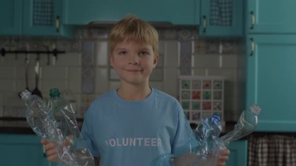 Menino em azul Voluntário T-shirt classificando garrafas de plástico em recipientes com sinal de reciclagem verde. Processo de reciclagem em casa. Fácil de reciclar. — Vídeo de Stock