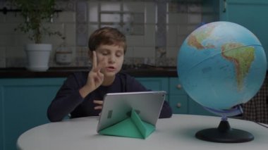 10 yaşında otizmli bir çocuk evde oturup tablet bilgisayar kullanarak internetten öğreniyor. Otizmli çocuklar için evde eğitim.