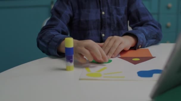 Κοντινό πλάνο δημιουργικού σχολιαρόπαιδου που φτιάχνει απλικέ τέχνης με έγχρωμο χαρτί και κόλλα. Παιδική δημιουργικότητα στο σπίτι. — Αρχείο Βίντεο