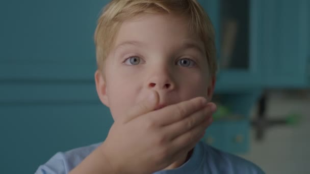 Zszokowany dzieciak otwierający usta i zamykający je ręką. Chłopiec z przedszkola pokazuje szok lub wow emocje patrząc w aparat. Portret rozbawionego dziecka. — Wideo stockowe
