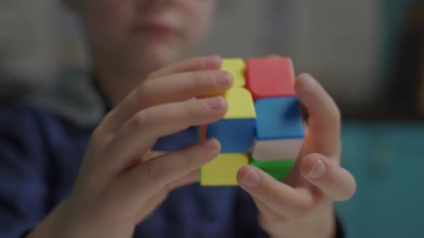 Zbliżenie chłopca w okularach szkolnych rozwiązywanie układanki kolor sześcian w dłoniach. Inteligentne dziecko bawi się puzzle sześcian. — Wideo stockowe