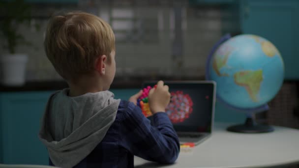 Skolpojke spelar färg leksaker gör modell av virus sitter hemma. Grabben använder surfplatta för att modellera virus med leksaker. — Stockvideo