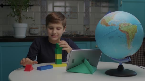 Autistic boy building con bloques de madera de color usando tableta de computadora. Asignación en línea a un alumno con autismo. Análisis de comportamiento aplicado para estudiantes con autismo. — Vídeos de Stock