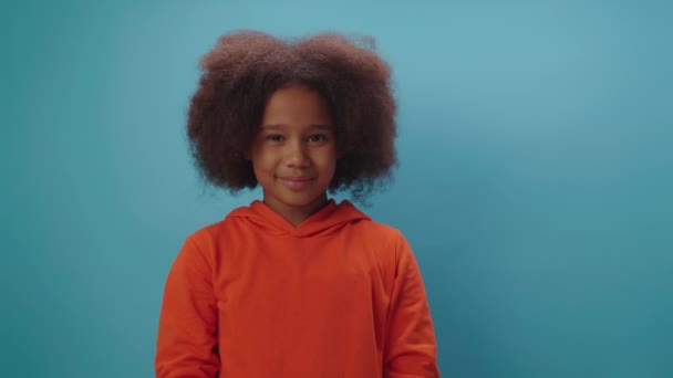 Menina afro-americana bonito fazendo gesto de silêncio com indicador por boca no fundo azul. Retrato de criança mostrando silêncio e sinal tranquilo com o dedo. — Vídeo de Stock