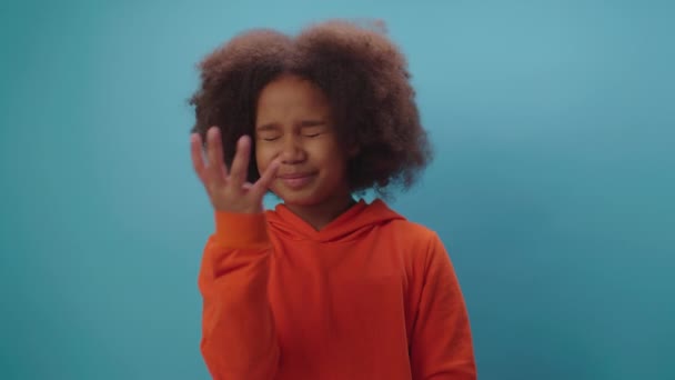 アフリカ系アメリカ人の少女は、青の背景に立って不信、憤慨、恥、刺激または不快感を表す顔のヤシのジェスチャーを作ります. — ストック動画