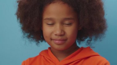 Afro-Amerikan kızlarının yüz hareketlerini kapatın. İnançsızlığını, bıkkınlığını, utancını, asabiyetini ve sıkıntısını ifade edin. Mavi arka planda durun..