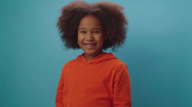 İki portakal meyvesi tutan mutlu Afrikalı Amerikalı kız mavi arka planda duran yüzü duyuyor. Komik turuncu gözlü siyah çocuk.. 