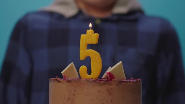 Primer plano del niño soplando la vela número 5 en cámara lenta. Un niño de cinco años celebra su cumpleaños. Feliz 5 años de edad. — Vídeo de stock