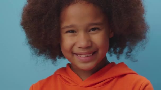 Close up of cute African American girl shaking her head negative saying No standing on blue background. Kid disagrees by moving her head. — Stockvideo