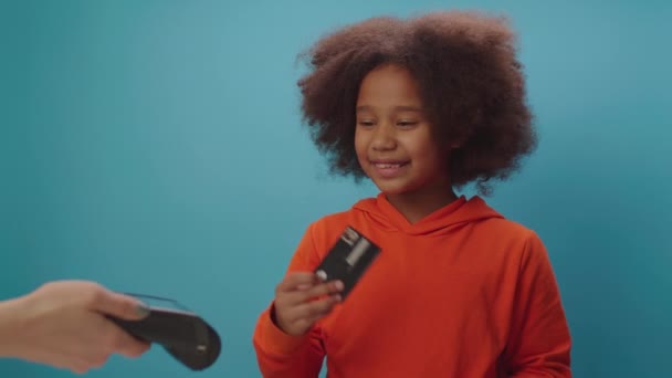 Afroameričanka platí kreditkou a bezkontaktním terminálem. Šťastné dítě, které používá NFC. Dítě používající svou bankovní kartu. — Stock video