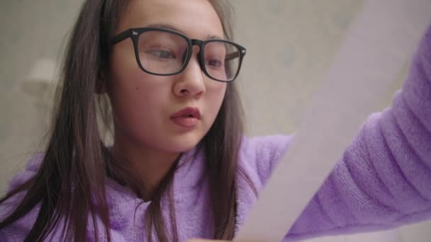 Közel a feldúlt húszas évekbeli ázsiai nő szemüveg nézi nagy üzlet blokk. Frusztrált millenniumi női számviteli családi költségvetés. — Stock videók