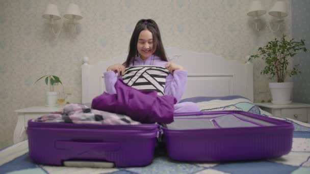 Neşeli Asyalı kadın yaklaşan deniz tatilinden çok mutlu. Elinde mayo, rüyasında evde yatakta oturuyor.. — Stok video