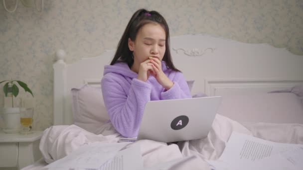 Mooie Aziatische vrouw denken met behulp van laptop zitten in bed. Exited vrouwtje heeft een goed idee en typen op laptop. — Stockvideo