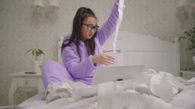 20 'li yaşlarda, gözlüklü Asyalı bir kadın yatakta oturan fişe bakıyor. Milenyum kadın muhasebe bütçesi hayal kırıklığına uğradı..