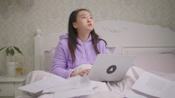 Vermoeide Aziatische vrouw die thuis werkt met laptop en documenten in bed. Boos vrouw werken remote verblijf in bed thuis. — Stockvideo