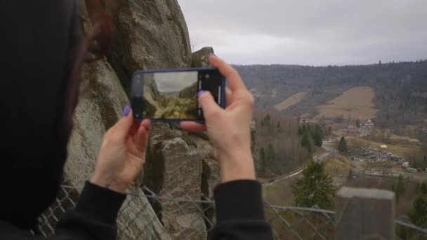 Mulher tirando fotos da paisagem da montanha segurando o telefone celular nas mãos. Sobre a visão do ombro da pessoa fazendo foto na célula. — Vídeo de Stock