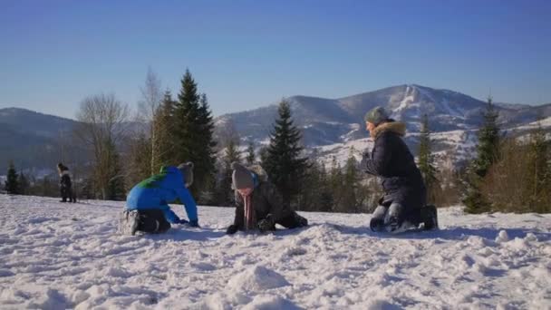 Семья матери и двое сыновей играют со снегом на вершине горы. Зимний отдых. Мама играет с детьми на улице. — стоковое видео
