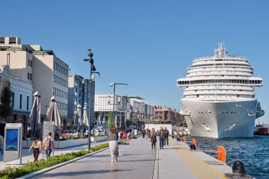ISTANBUL, TURKEY, 9 Mayıs 2022: Galataport 'ta deniz kenarında yürüyen insanlar, sağ tarafta büyük bir yolcu gemisi görülebilir. Galataport, Karaköy bölgesinde bir yolcu gemisi limanıdır..