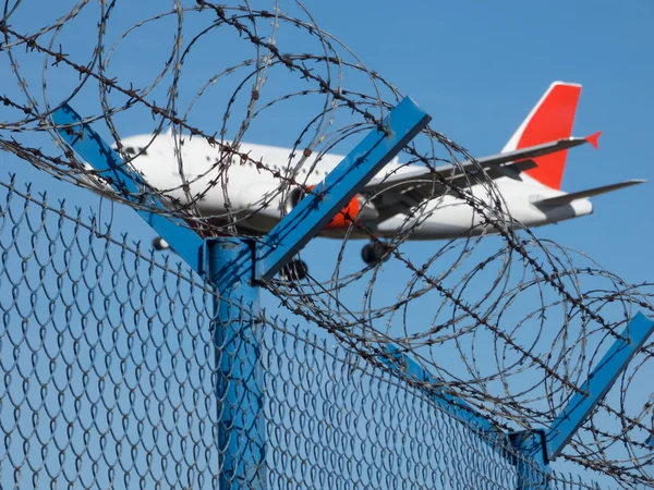 Landing airplane behind barbed wire — Stock Photo, Image