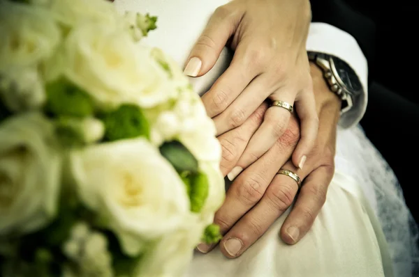 Two wedding hands with rings and white flowers