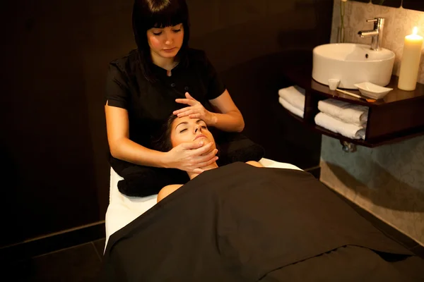 Mujer dando un masaje facial durante el tratamiento de spa . — Foto de Stock