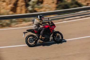 Almeria, İspanya - 5 Mayıs 2021: Almeria, İspanya 'da Dunlop Xperience etkinliği sırasında Yamaha Tracer 7 motosikletli bir adam güzel virajlar arasında bir dağ yolunda.
