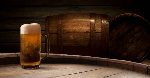 Beer. Still life with Vintage beer barrel and glass light beer. Fresh amber beer concept. Green hop and gold barley on wooden table. Ingredients for brewery. Brewing traditions