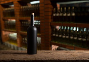 Boş şarap şişeleri ve ahşap masada bir bardak kırmızı üzüm.