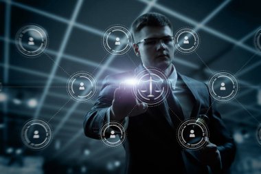 Young lawyer clicks on the scales of justice icon on a dark background.