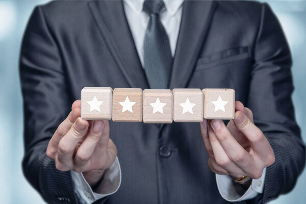 Businessman showing five stars rating on blurred background.