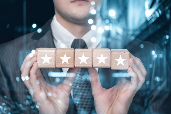 Business man shows 5 stars in cubes on a blurred background.