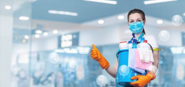 Temizlikçi kadın ellerinde deterjanla arka planda bulanık görünüyor..