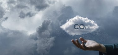 Concept protection of nature CO2. The hand shows the clouds with the inscription CO2 against the sky background.