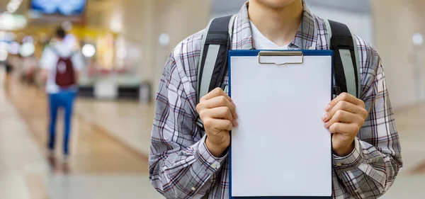 A student shows an empty sheet for the schedule on a blurred background.