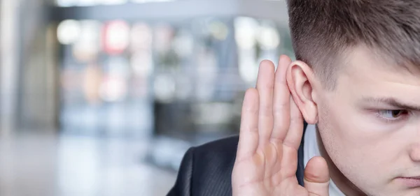 Zakenman Legde Zijn Hand Zijn Oor Luistert Een Wazige Achtergrond — Stockfoto