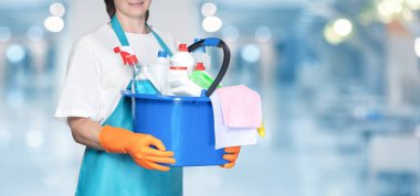 A cleaning lady with a cleaning tool stands on a blurred background.