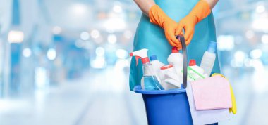 Cleaner holding a bucket of cleaning products for cleaning on a blurred background.
