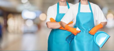 A group of cleaners stand in front of a blurred background of a shopping mall.