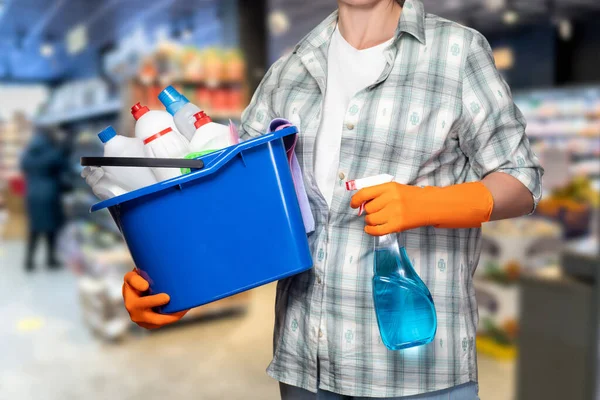 A cleaning lady with a bucket and cleaning products stands in front of a cafe.