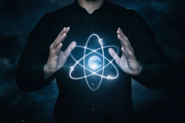 Concepts management peaceful atom. A man manipulates an atom on a dark background.