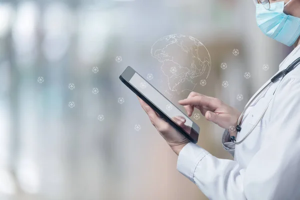 Doctor working on a tablet with a global medical network on a blurred background.
