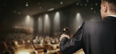 Müzayedecinin biri büyük bir salonda alıcılarla açık artırma düzenliyor..