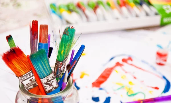 Färgglada penslar med färg i bakgrunden — 图库照片