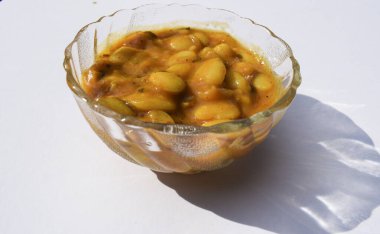 Beyaz arka planda şeffaf kasede servis edilen lezzetli Vaal nu shaak veya tereyağlı fasulye körisi. Lezzetli Hint usulü körili fasulye ya da bakla