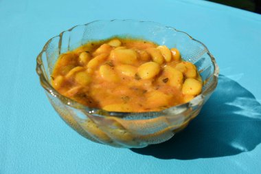 Lezzetli Vaal nu shaak veya tereyağlı fasulye körisi mavi arka planda şeffaf kasede servis edilir. Lezzetli Hint usulü körili fasulye ya da bakla