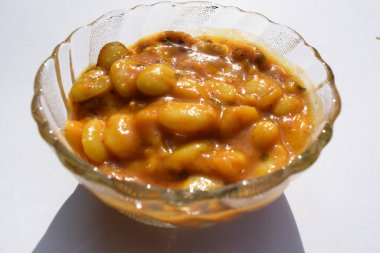 Beyaz arka planda şeffaf kasede servis edilen lezzetli Vaal nu shaak veya tereyağlı fasulye körisi. Lezzetli Hint usulü körili fasulye ya da bakla